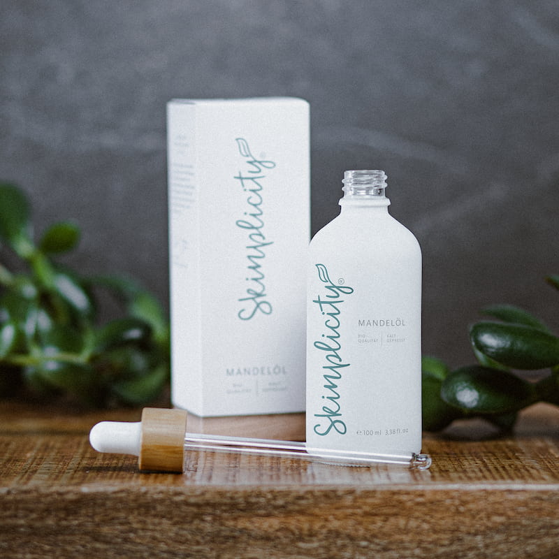 Bio-Mandelöl für Gesicht, Haut und Haar mit Pipette auf Holzuntergrund